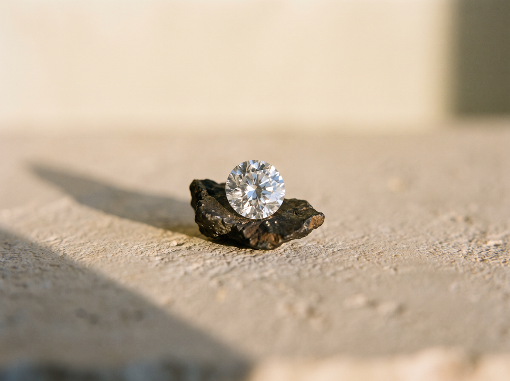 A brilliant-cut moissanite resting on a fragment of meteorite