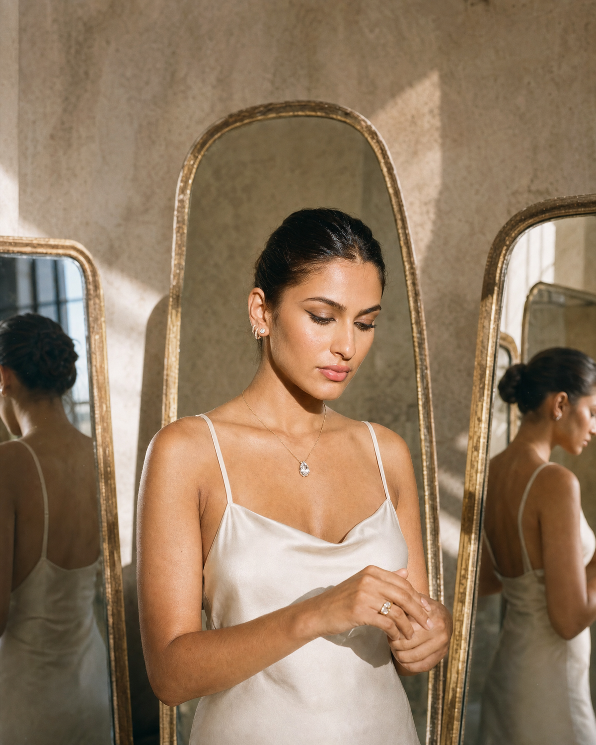 A woman in ivory silk among tall mirrors, her reflection repeated